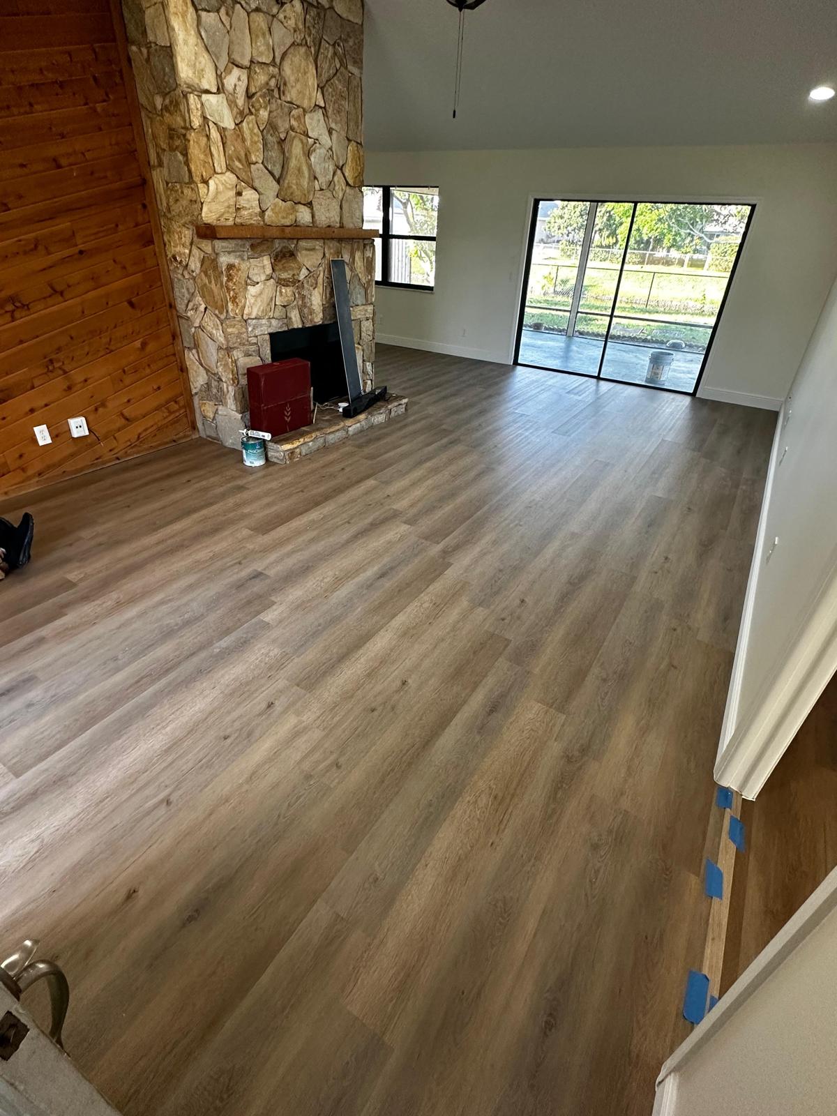 Finished warm oak LVP living room with vaulted ceiling and stone fireplace