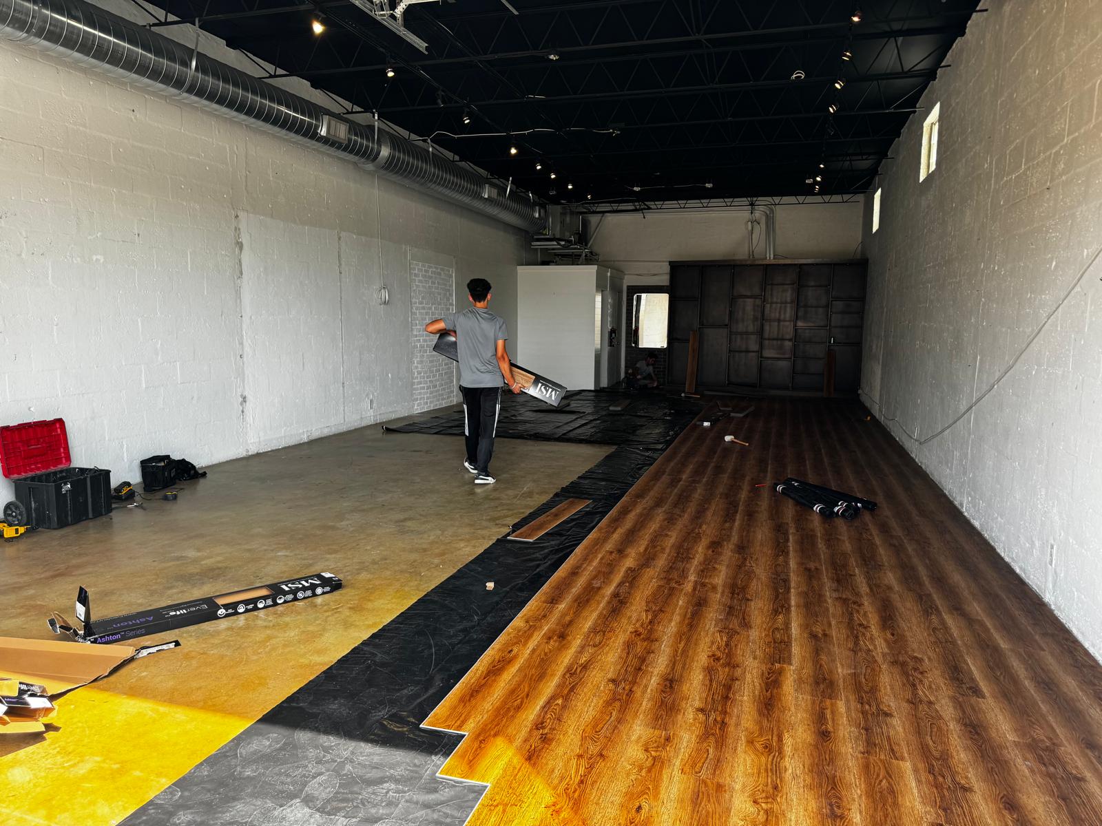 Commercial showroom install in progress with rich brown wood-look LVP