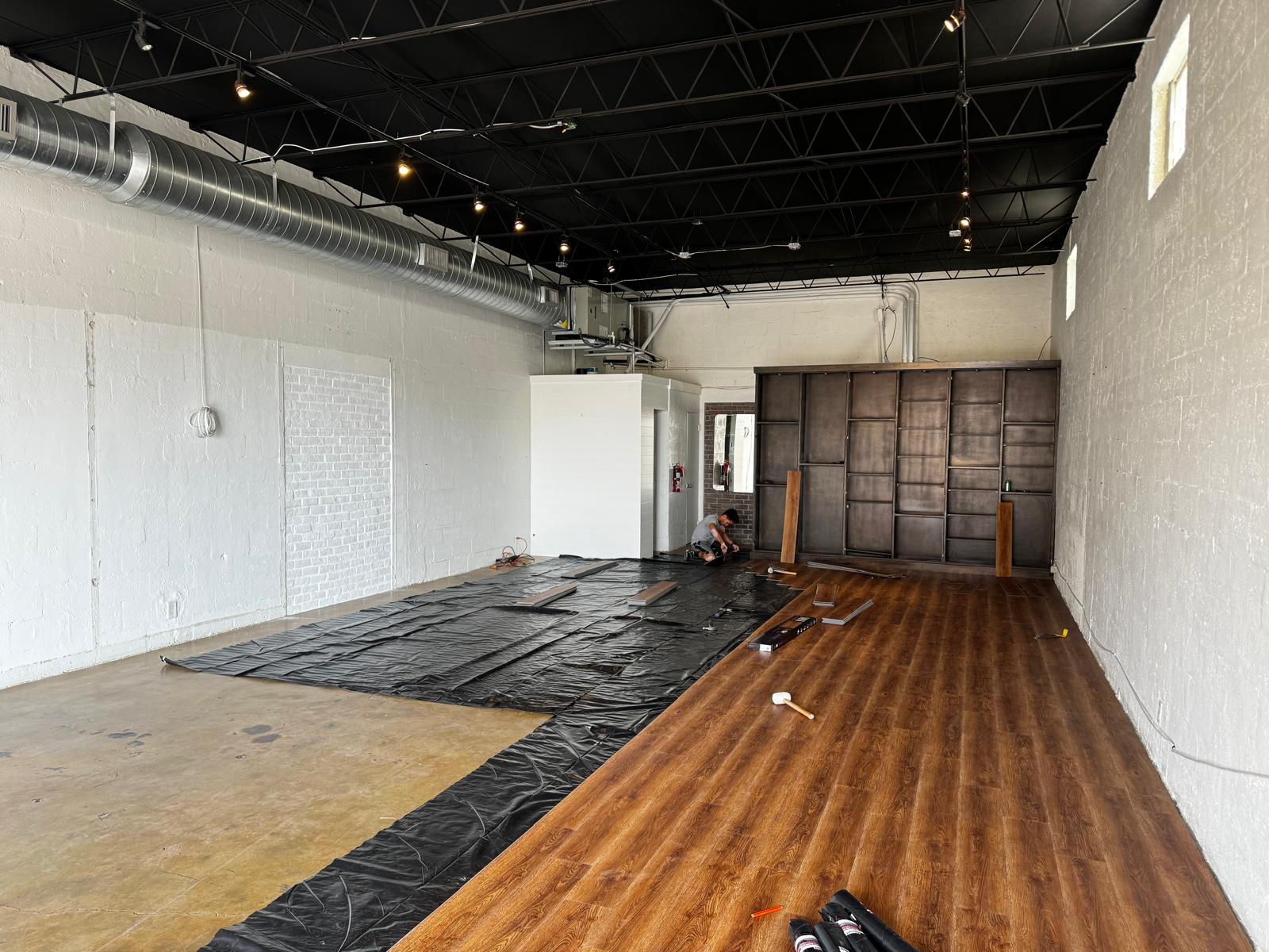 Commercial space mid-install with rich oak LVP next to feature wall