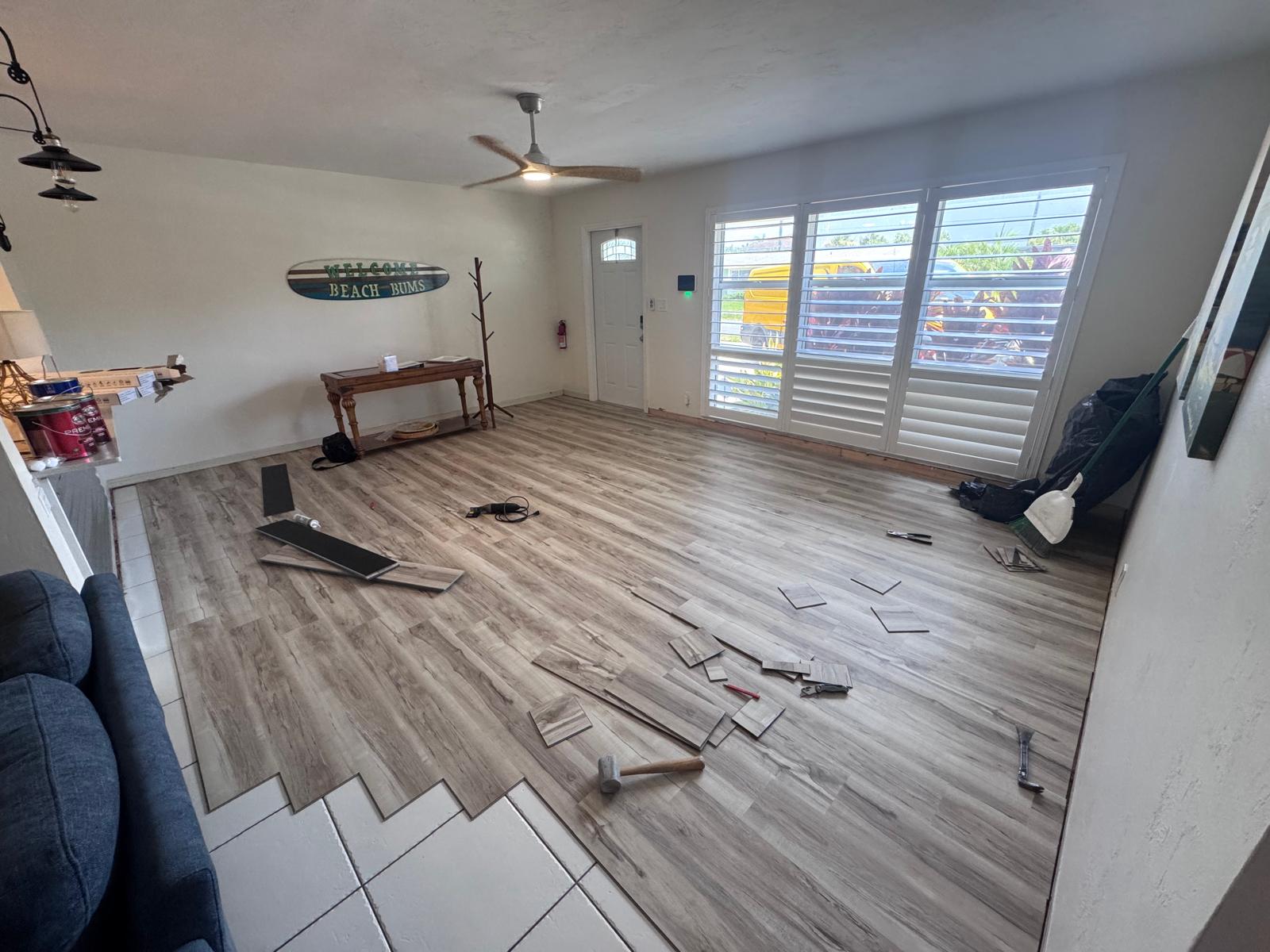 Wide-plank LVP being installed mid-room with planks staged for the next row