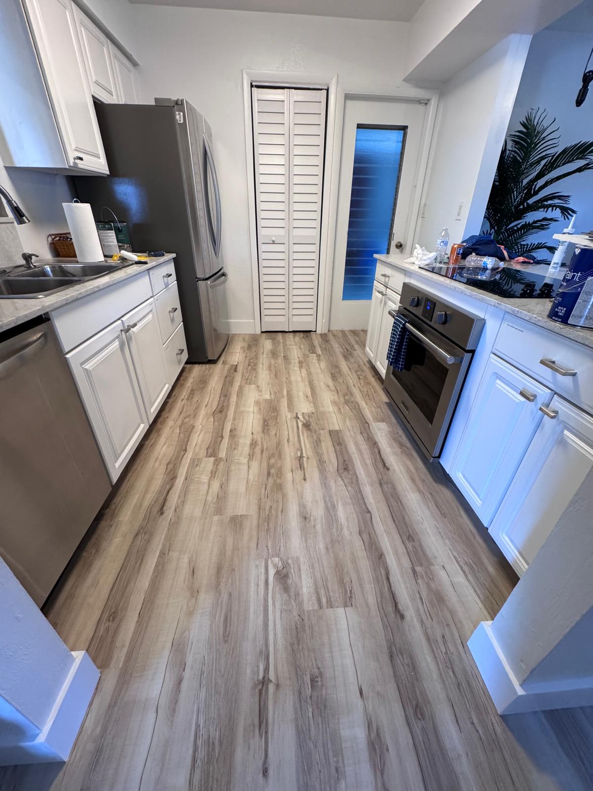 Galley kitchen with new wood-look LVP and white cabinets